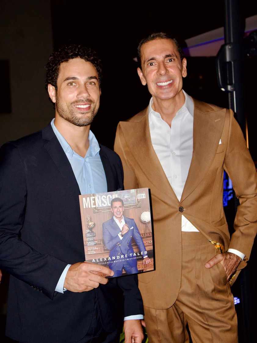 Dois convidados posando com revista durante evento no The Roof 448